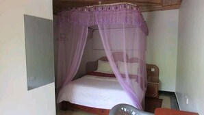 A single bed with a canopy, a nightstand, and a wall-mounted light fixture. - Kape Samaritan Guest House (Makutano)