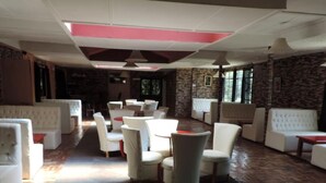 A spacious lounge area with white upholstered seating and a herringbone-patterned wooden floor. - Lions Court Lodge (Nanyuki)