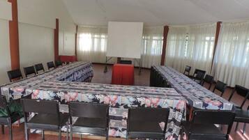 A conference room with a long table, black chairs, and a projector screen.