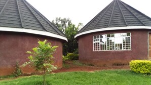 Two round buildings with dark roofs and white trim, surrounded by green grass and a small tree. - Mseven Gardens M7 (Nyahururu)