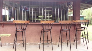 A bar area with a counter and four metal barstools. - Mseven Gardens M7 (Nyahururu)