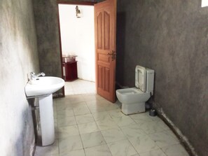 A bathroom with a white sink, a toilet, and a wooden door. - Mseven Gardens M7 (Nyahururu)