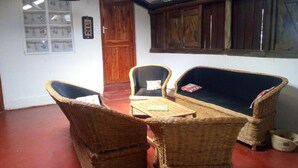 A room with wicker furniture, a wooden door, and a window with wooden shutters. - Muremba Retreat Kitale (Kitale)