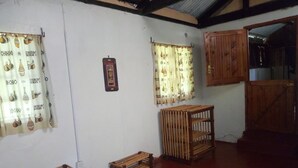 A rustic room with wooden furniture, patterned curtains, and a wooden door. - Muremba Retreat Kitale (Kitale)