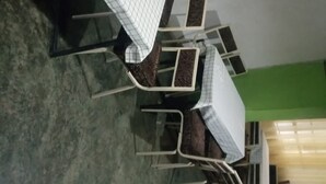 A dining area with tables and chairs, a green wall, and a window with curtains. - Mwaki-Mugi Hotel & Campsite (Nakuru)