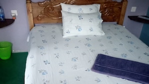 A bed with a floral bedspread, a wooden headboard, and a green trash bin. - Mwaki-Mugi Hotel & Campsite (Nakuru)