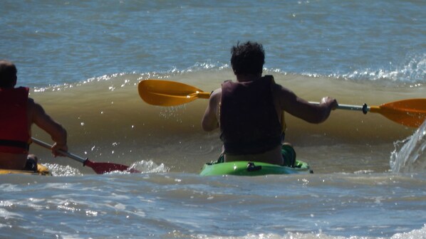Dos personas remando en kayak por un río.