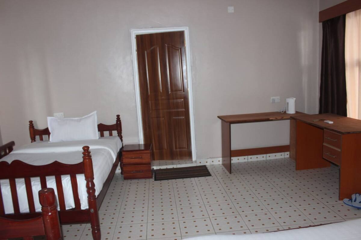 A bedroom with a wooden bed, a desk, and a door.