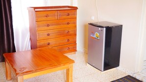 A small wooden dresser with drawers and a refrigerator with a sticker. - Namelok Retreat Centre (Nyahururu)