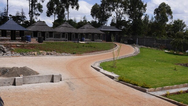 A residential area with a curved driveway leading to a house with a thatched roof. - Namelok Retreat Centre (Nyahururu)