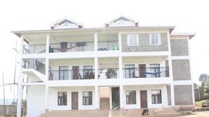 A multi-story residential building with balconies, a brick base, and a flat roof. - Namelok Retreat Centre (Nyahururu)