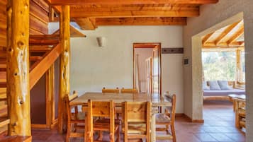 Un comedor de madera con una mesa grande y sillas, una escalera y vistas al exterior.