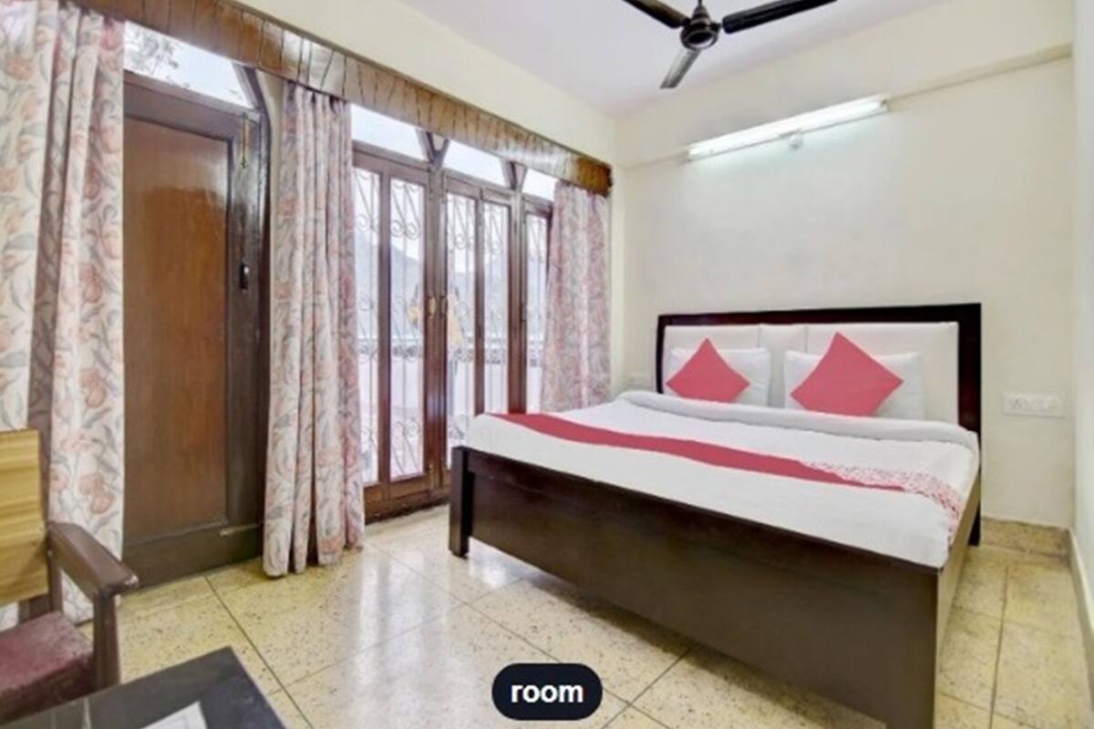 Un dormitorio con cama, cortinas, ventilador de techo y ventana.