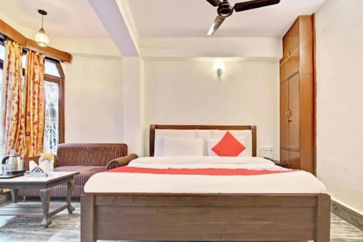 Una habitación de hotel con cama, sofá, mesa y ventilador de techo.