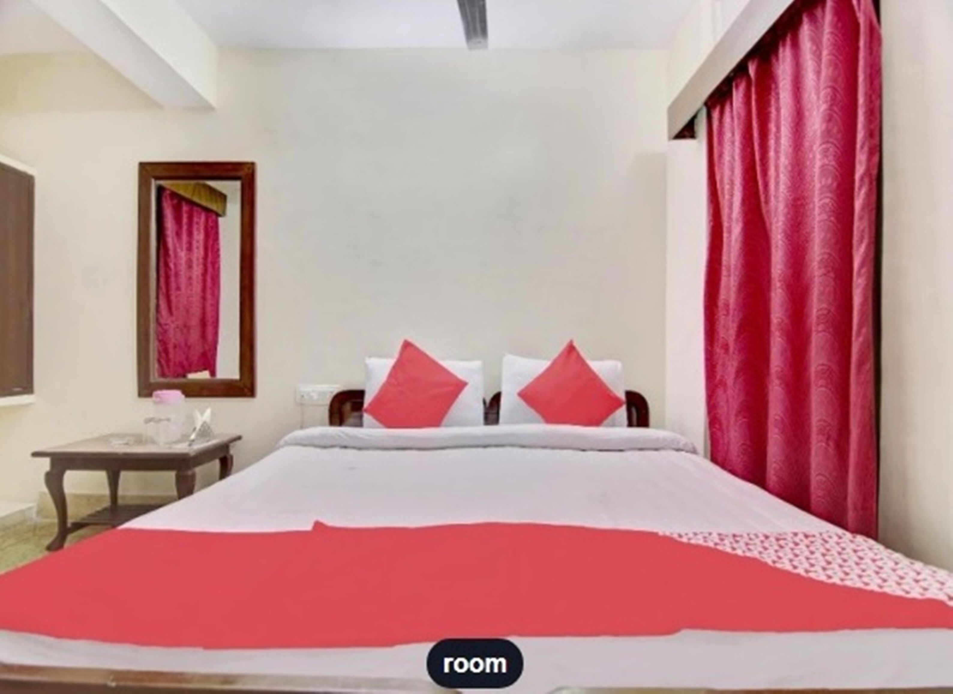 A hotel room with a bed, a nightstand, and a mirror.