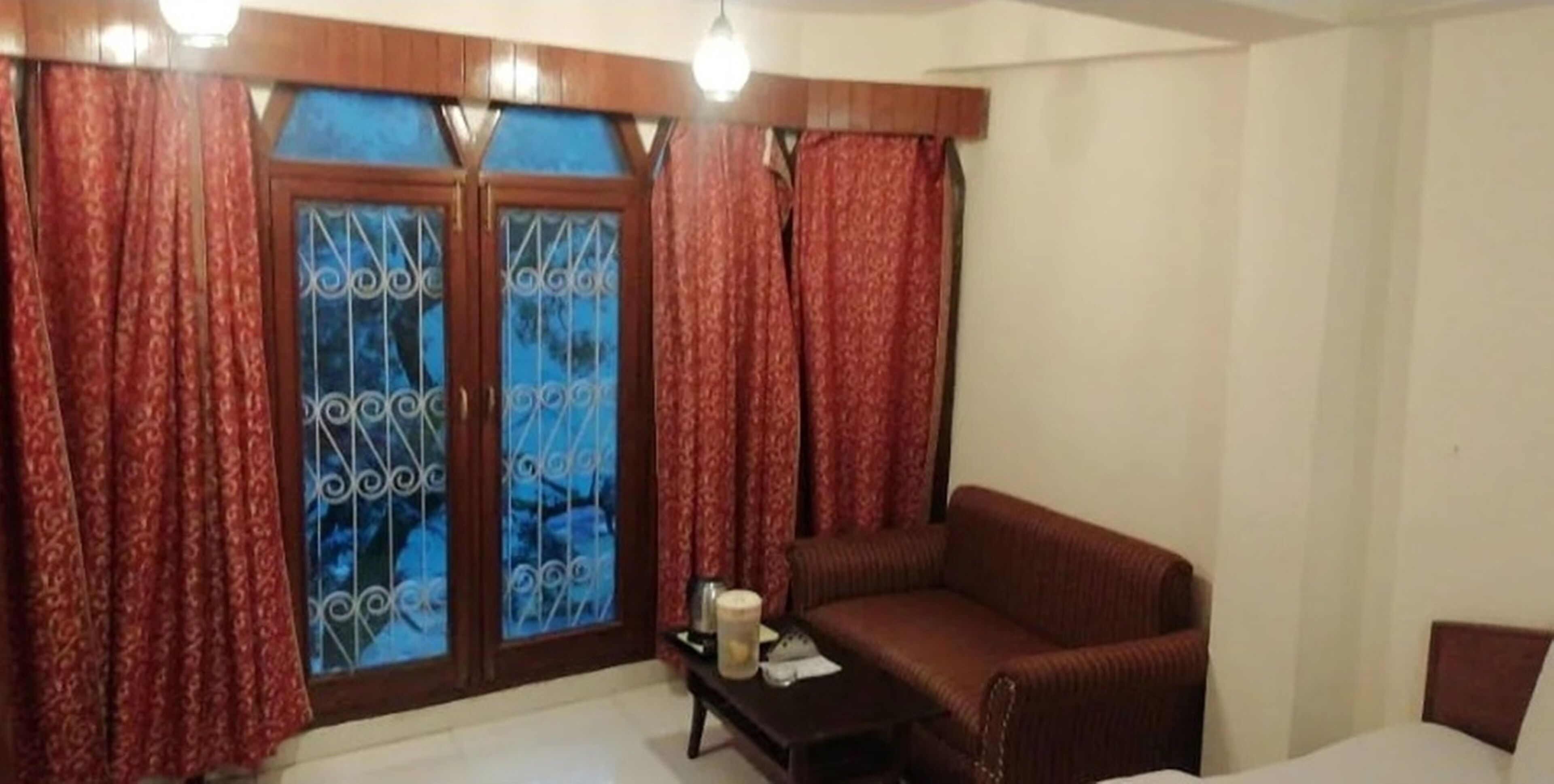 A living room with a sofa, a small table, and a window with curtains.