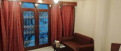 A living room with a sofa, a small table, and a window with curtains.