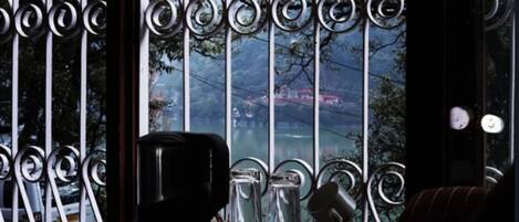 A room with a view of a lake and mountains, a metal gate, and a coffee maker on the table.