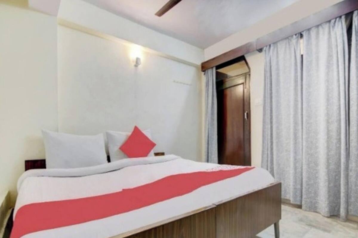 Un dormitorio con cama, un armario de madera, una puerta y una ventana con cortinas.
