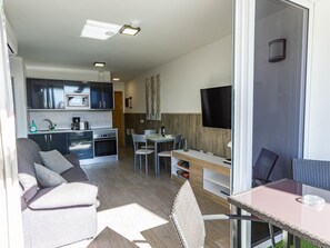 A compact living space with a kitchenette, dining area, and a TV.