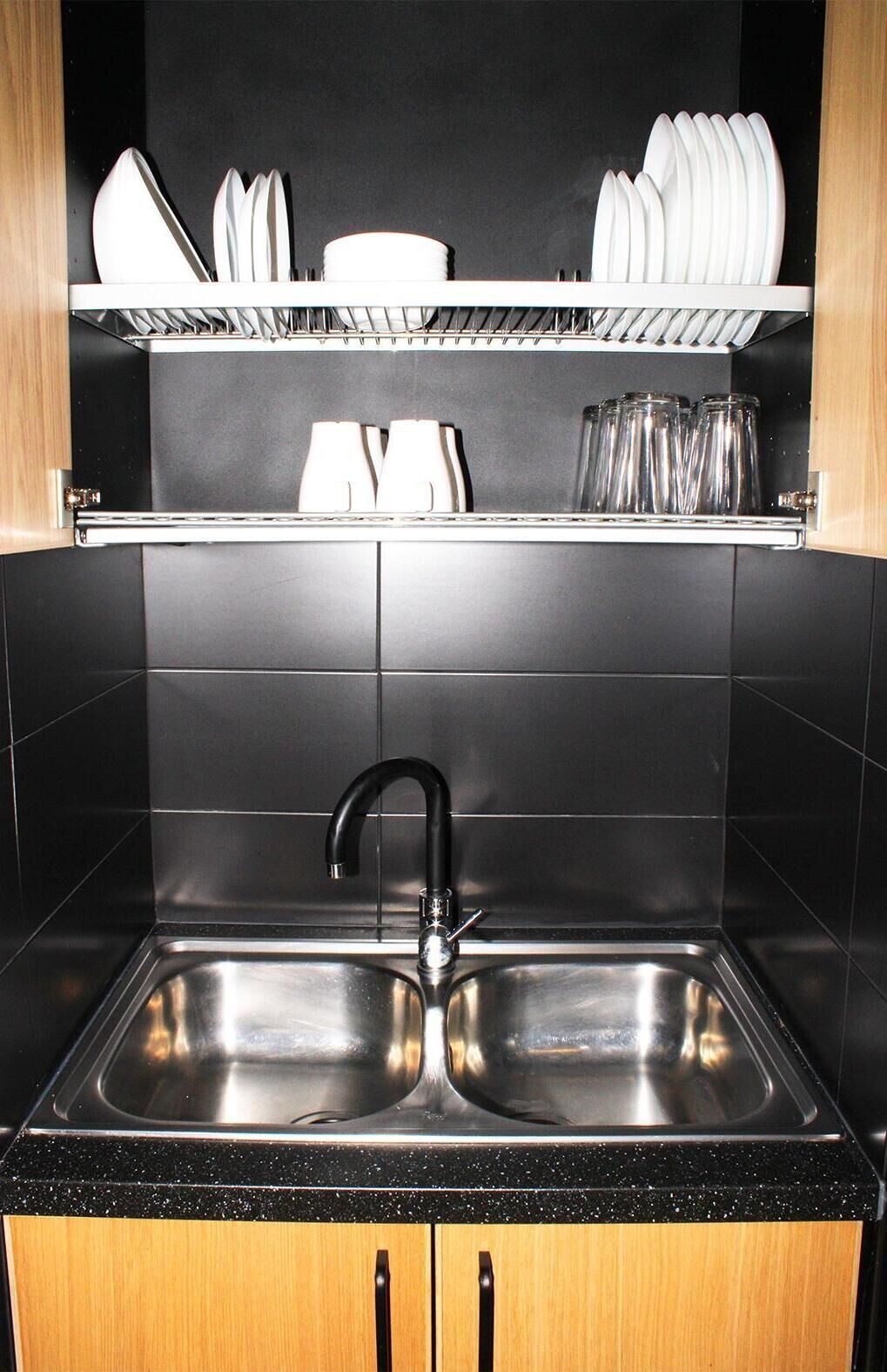 Una cocina con un lavamanos doble, salpicadero de azulejos negros y armarios de madera.