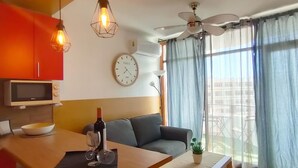 Un soggiorno moderno con un divano, un tavolo da pranzo, una ventola a soffitto e un'ampia finestra con tende.