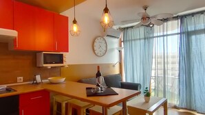 Una cucina moderna con mobili rossi, un forno a microonde, un'area pranzo con sgabelli di legno e un'ampia finestra con tende.
