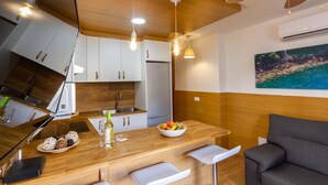 A modern kitchen with wooden cabinets, a central island with bar stools, a ceiling fan, and a painting on the wall.