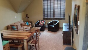 A cozy living area with a wooden dining table, two black armchairs, a sofa, and a window with blinds. - Bear Lake with View Guest House, Above Garage in Beautiful St. Charles (St Charles)