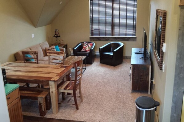 A cozy living area with a wooden dining table, two black armchairs, a sofa, and a window with blinds. - Bear Lake with View Guest House, Above Garage in Beautiful St. Charles (St Charles)