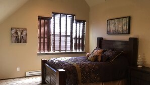 A bedroom with a large bed, a window with blinds, a radiator, and a painting on the wall. - Bear Lake with View Guest House, Above Garage in Beautiful St. Charles (St Charles)
