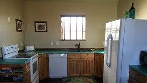 A compact kitchen with wooden cabinets, a white refrigerator, a dishwasher, and a window with blinds. - Bear Lake with View Guest House, Above Garage in Beautiful St. Charles (St Charles)