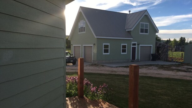 A two-story house with a front deck, garage, and a grassy yard. - Bear Lake with View Guest House, Above Garage in Beautiful St. Charles (St Charles)
