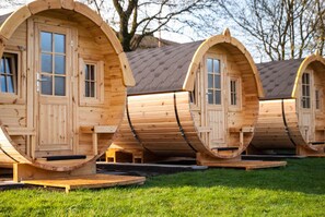 A row of wooden pod-style cabins with windows and doors, each elevated on a platform. - Harmony beim Holzschnitzer (Dreis-Brück)