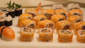 A variety of sushi rolls and shrimp on a white platter. - Harmony beim Holzschnitzer (Dreis-Brück)