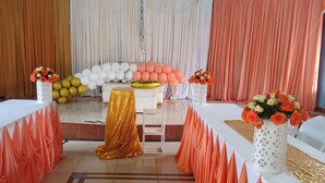 A decorated event space with a stage, white and gold table settings, and floral arrangements. - Superbreak Hotel (Kitale)
