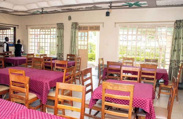 A dining area with wooden tables and chairs, covered with checkered tablecloths. - Superbreak Hotel (Kitale)