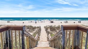 A wooden staircase leading to a beach with a clear sky.