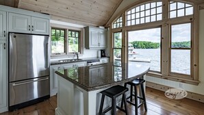Eine Küche mit einer großen Kochinsel, Edelstahlgeräten und Seeblick durch große Fenster.