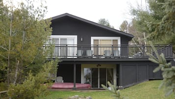 A two-story house with a balcony, a covered patio, and a red couch.