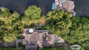 Vista aérea de una casa con piscina, rodeada de árboles frondosos.