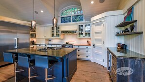 Una cocina moderna con una isla grande, taburetes de bar, electrodomésticos de acero inoxidable y armarios blancos.