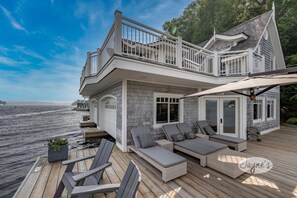 Een pand aan het water met een terras, buitenmeubels en uitzicht op het water.