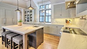 A modern kitchen with a large island, pendant lighting, and a view of the outside. - Ultimate Boathouse Entertaining, New 6 bdrm, 8 bath Cottage/Boathouse! Hot tub! (Port Carling)