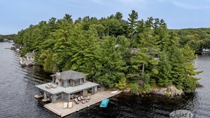 A lakeside cabin with a dock, surrounded by dense forest. - Ultimate Boathouse Entertaining, New 6 bdrm, 8 bath Cottage/Boathouse! Hot tub! (Port Carling)