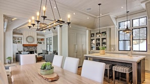 A spacious kitchen with a large island, pendant lighting, and a view of the outdoors. - Ultimate Boathouse Entertaining, New 6 bdrm, 8 bath Cottage/Boathouse! Hot tub! (Port Carling)