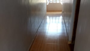 A narrow hallway with wooden flooring and white walls. - 2030 Guest House (Nakuru)