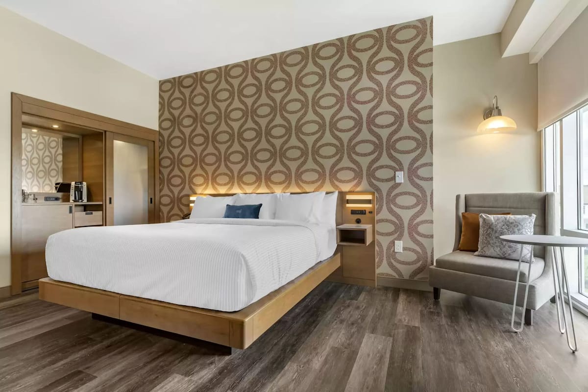 Een moderne hotelkamer met een groot bed, een kleine zithoek, een bureau en een spiegel.