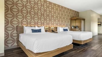 A hotel room with two beds, a patterned wall, and a wooden floor.