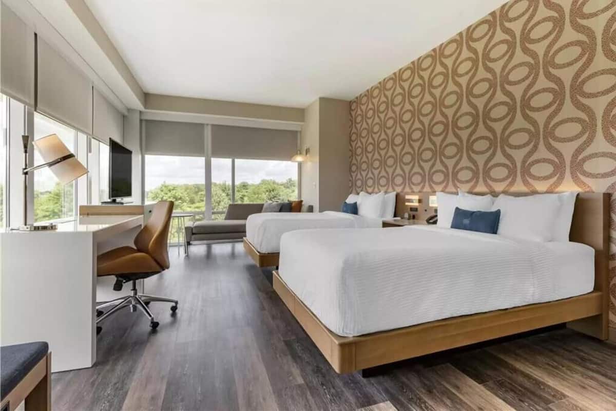 Ein Hotelzimmer mit zwei Betten, einem Schreibtisch und einem Fernseher.